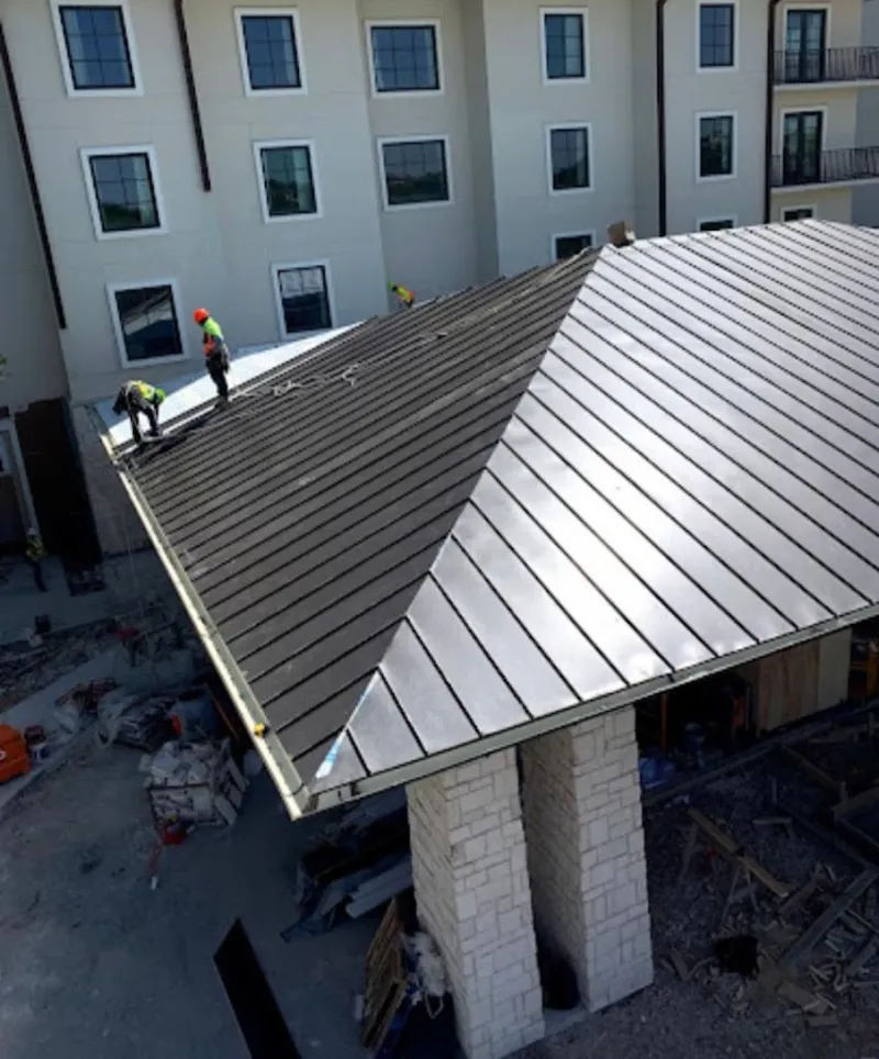 Crew installing standing seam metal roof panels on a commercial project in New Gloucester